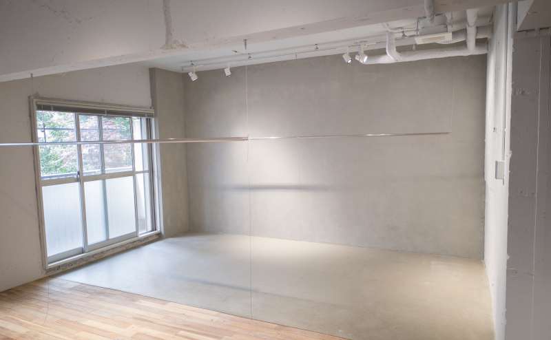 モルタル壁×モルタル床エリア｜部屋中央のワイヤー吊り下げ式ラックは幅2.7m