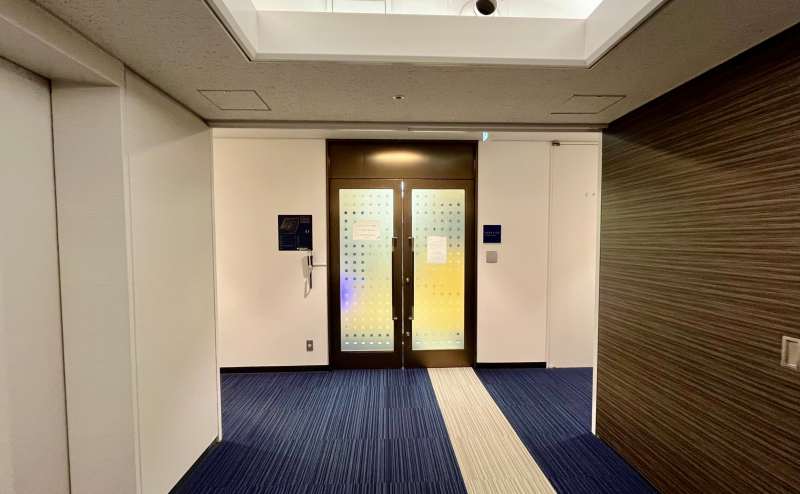 【左手にある共用扉の前で、予約完了メールに記載のAkerunのURLを開き「開ける」ボタンを押すと開錠されます】