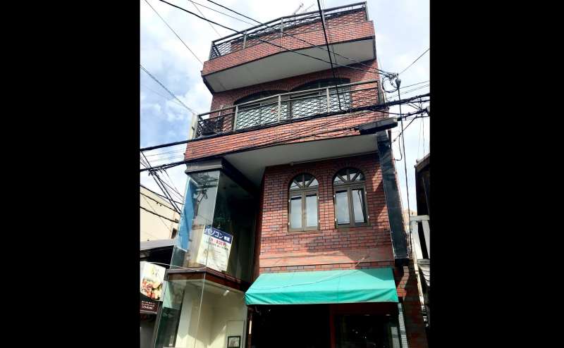 茶色のレンガの建物の2階にございます。