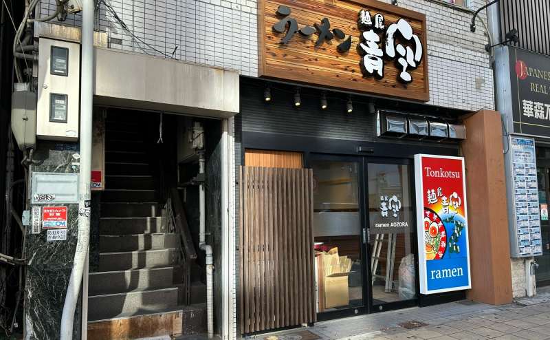 「ラーメン青空」の左にある階段で指定の部屋へお進みください。