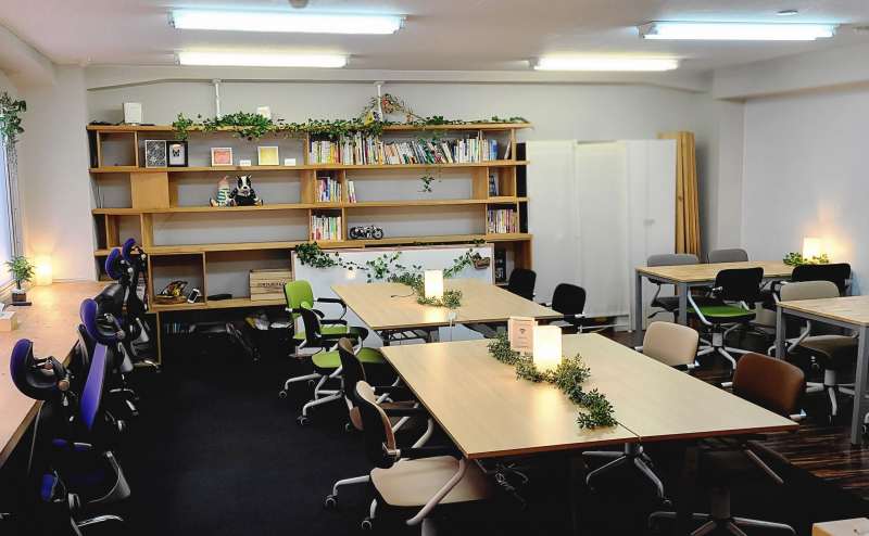 (ホワイトボード有)オフィスエリア半面プランは手前から奥(本棚側)までの約22席利用可能！ 真ん中の4人掛けテーブルは折りたたみ・移動が可能なので必要に応じて席数を増やせます。