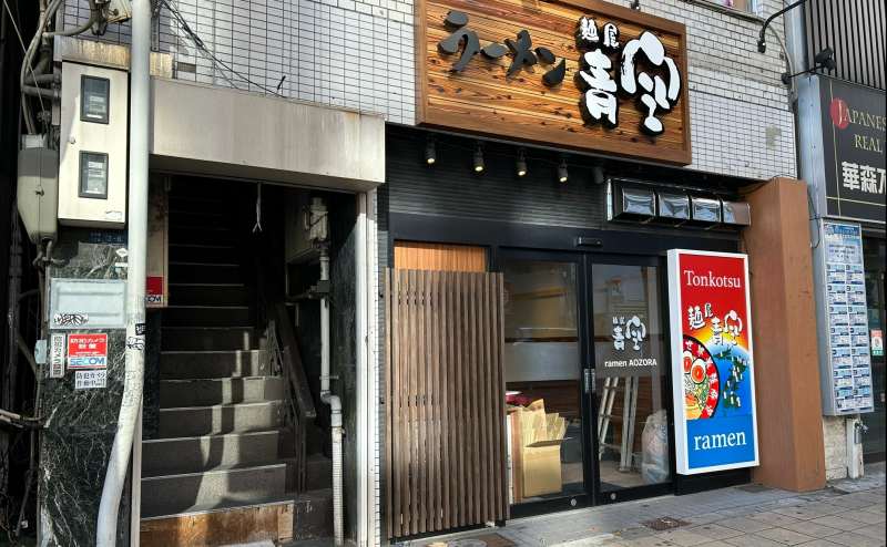 「ラーメン青空」の左にある階段で指定の部屋へお進みください。